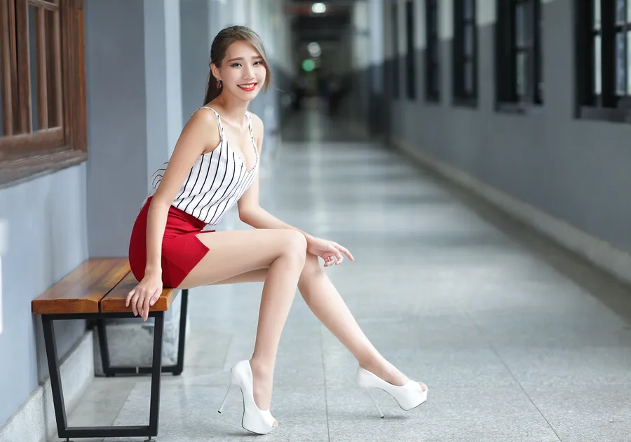 穿著紅色短褲和白色高跟鞋的女性坐在走廊的長椅上。