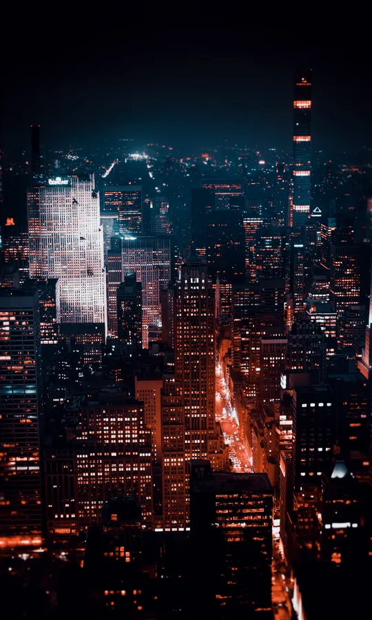夜間城市景觀,有明亮的摩天大樓和發光的街道。