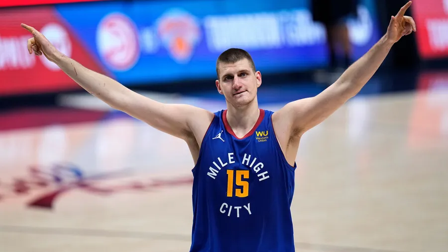 籃球運動員穿著印有「Mile High City」和號碼15的藍色球衣在球場上慶祝勝利。
