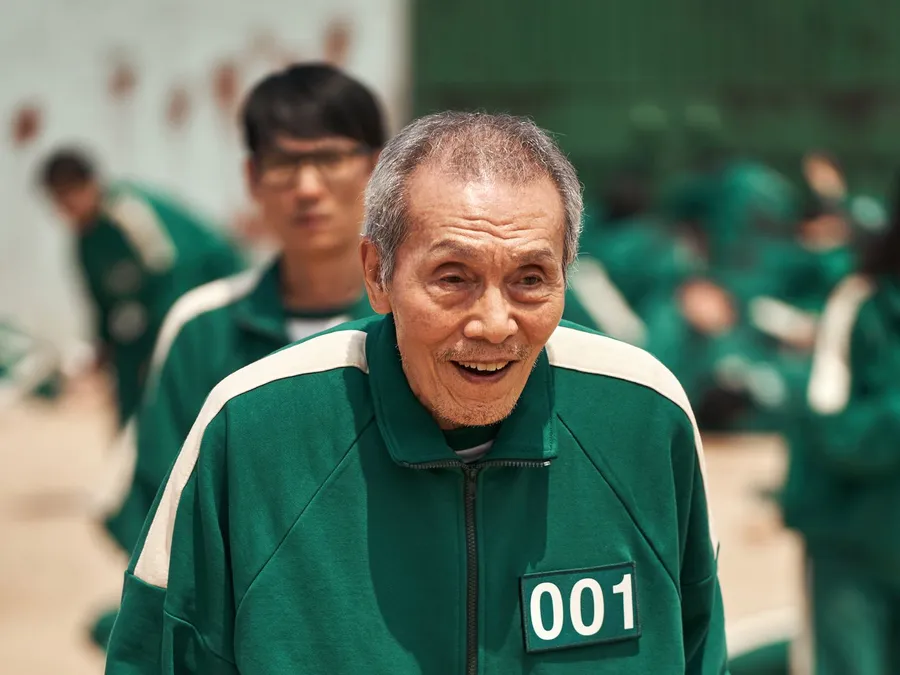 一位身穿綠色號碼運動服的長者在遊戲場景中燦爛地微笑。