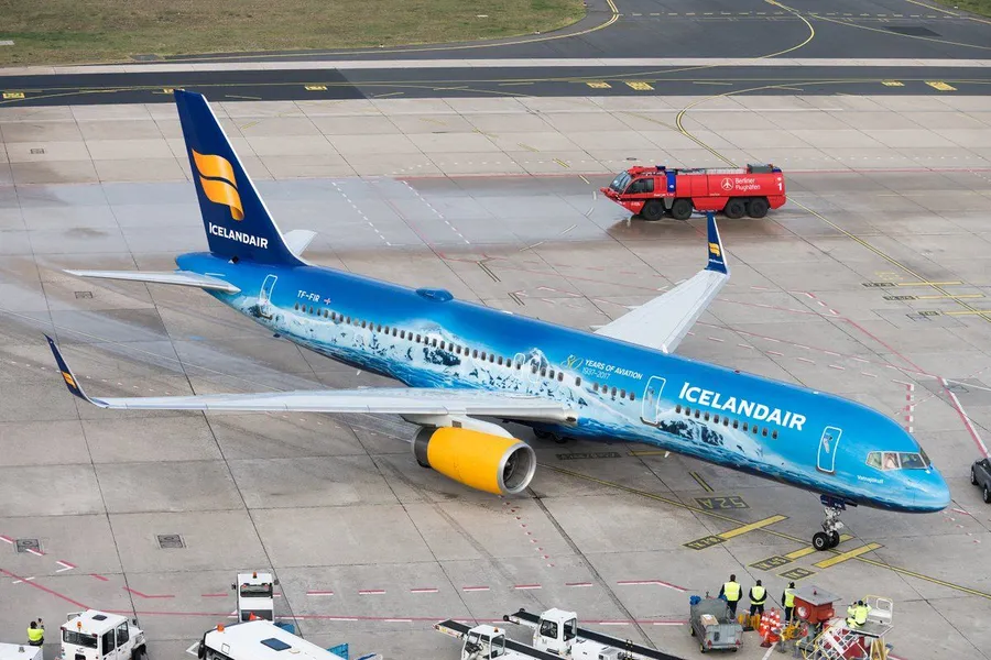 冰島航空飛機在機場停機坪上,有地勤人員和服務車輛