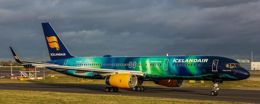 多雲天空下,停機坪上帶有極光設計的冰島航空飛機