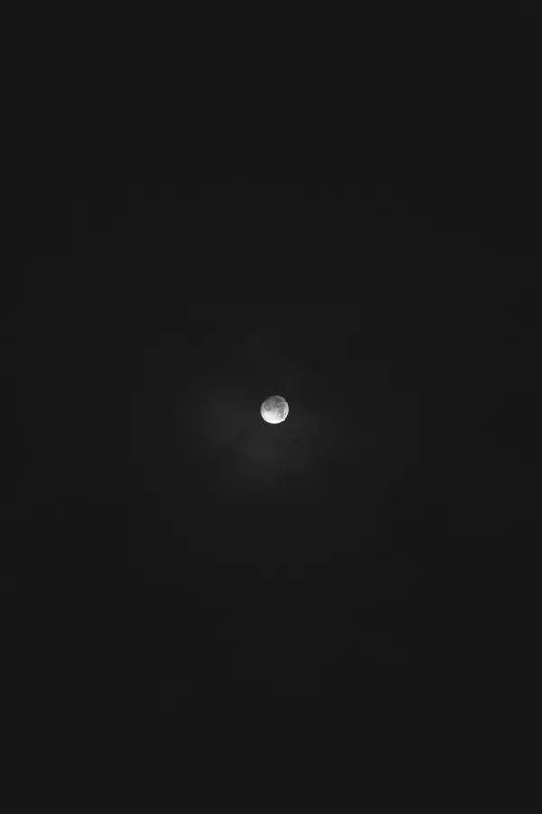 明亮的月亮在黑暗的夜空中透過薄雲閃耀。