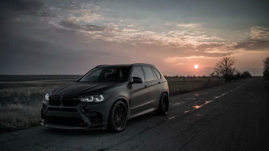 夕陽下潮濕鄉村道路上的啞光黑色BMW X5 M
