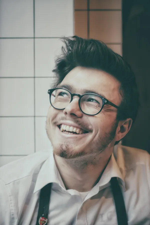 一位戴眼鏡和鬍子的微笑男子在瓷磚房間裡。