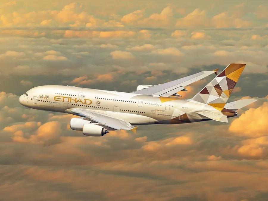 阿提哈德航空A380飛機在夕陽金色雲層上方飛行。