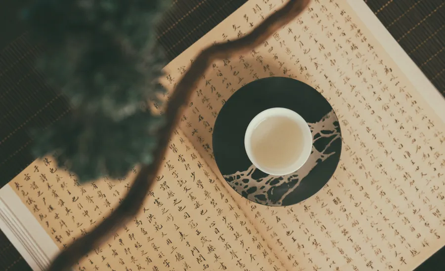 杯墊上的一杯茶,旁邊有一本手寫書和小植物。