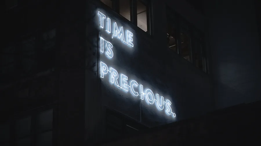 夜晚黑暗建築上寫著 time is precious 的霓虹燈牌。
