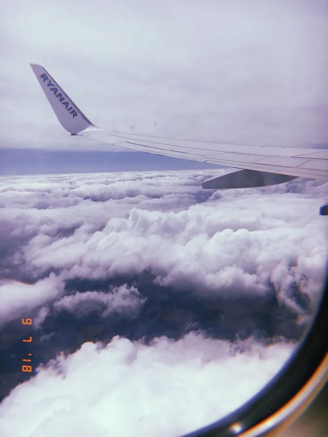 瑞安航空的機翼在雲層上方,從乘客窗戶看到,帶有菲林顆粒效果。