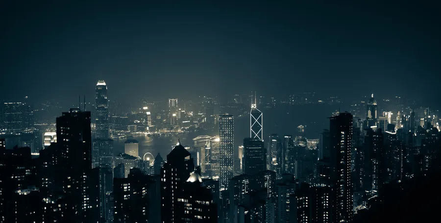 夜間城市景觀,有燈火通明的摩天大樓和黑暗的天空。