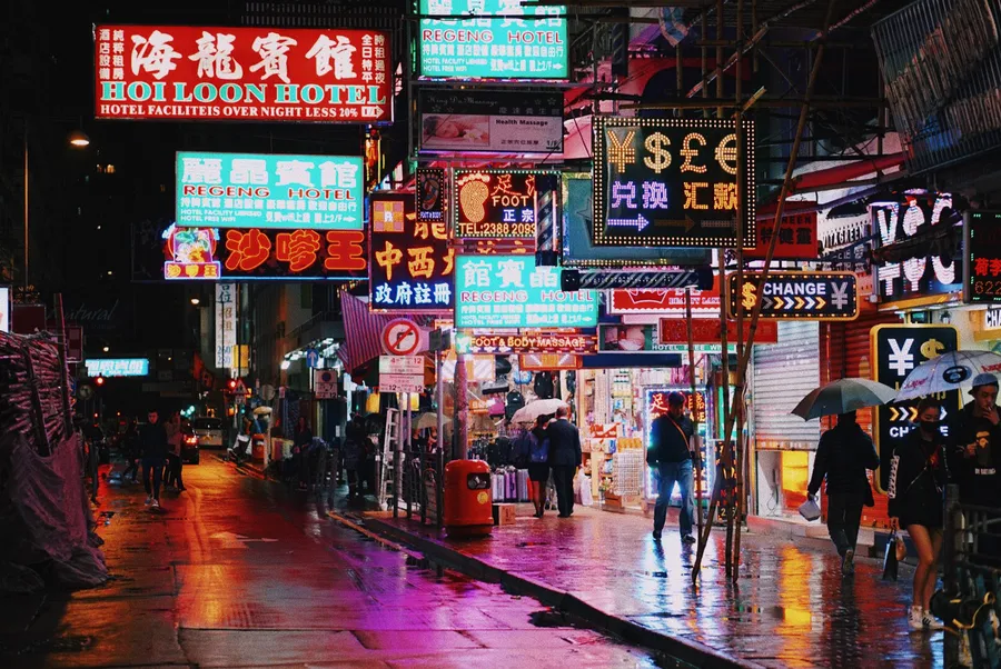 夜雨中的繁華霓虹城市街道,行人撐傘。