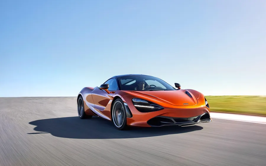 橙色McLaren跑車在日落時分的沙漠公路上疾馳。