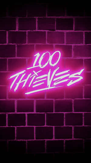 粉紅色霓虹燈牌寫著 100 THIEVES 在黑暗的磚牆上。
