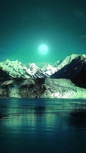 夜晚，在發光的青綠色月亮下的積雪山脈和冰川湖。