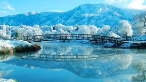 冬季平靜河流上的雪橋，映照山景。