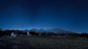 星空下，山巒背景中一個安靜的村莊夜晚。