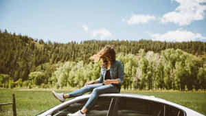 女性坐在車頂上，在陽光明媚的鄉村享受微風
