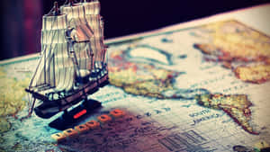 一個模型帆船放在復古世界地圖上，地圖上有木製字母拼出 travel。