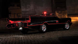 夜間停在鵝卵石街道上的黑色蝙蝠車，帶有紅燈。