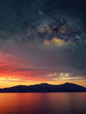 在星空和銀河下的暮色天空中，剪影山脈和水面 — 自然 壁紙