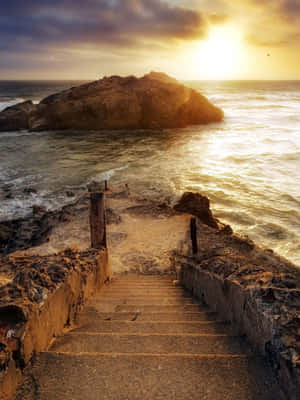 金色夕陽下，石階通往岩石島附近的海浪。 — 自然 壁紙