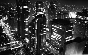 黑白模糊的夜晚城市天際線，閃爍的燈光。