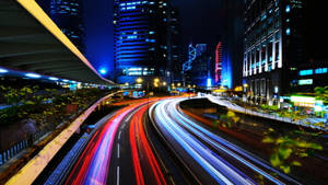 夜晚城市，帶有發光的車流軌跡和高聳的照明建築。