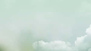 粉綠色天空，柔和白色雲朵平靜地飄動。