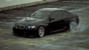 黑色BMW M3在濕滑混凝土上飄移冒煙。