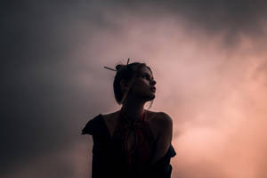 剪影中的女人看著帶有粉紅色和灰色雲彩的黃昏天空。 — 1920x1080 壁紙