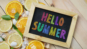 黑板上有「Hello Summer」，周圍有檸檬、橙、冰塊和貝殼在木頭上。 — 夏天 壁紙