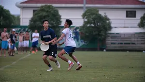 兩名運動員在草地上玩飛盤,觀眾在旁觀看。