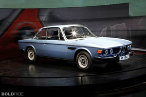 深色旋轉展示台上於攝影棚燈光下的淺藍色經典BMW 2002 tii。