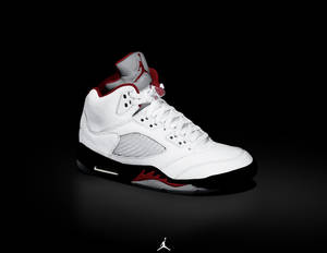 白色Jordan 5運動鞋，帶有紅色和黑色細節，背景為黑色