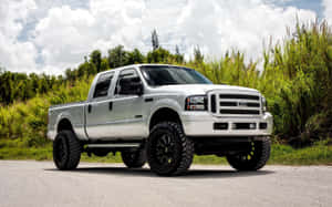 升高嘅銀色福特F-150 pickup貨車停泊喺碎石路，有綠色草叢同多雲天空。 — 汽車 壁紙