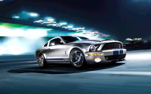 銀色 Shelby GT500 在夜間高速行駛，身後拖曳霓虹燈光。