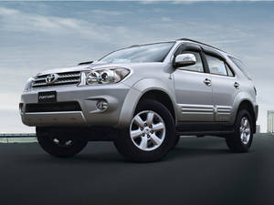 銀色豐田 Fortuner SUV 在道路上，背景為陰天。