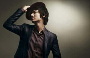 一位穿著西裝和帽子的男士在攝影棚環境中閉眼擺姿勢。