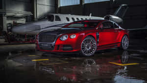 潮濕機庫中的紅色Mansory Bentley和私人飛機，帶有倒影。 — 汽車 壁紙