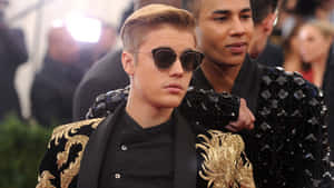 Justin Bieber 在正式活動中戴太陽眼鏡及穿金色刺繡外套。