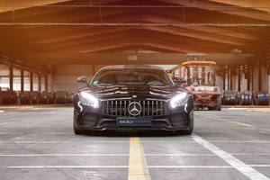 黑色Mercedes-AMG GT R停放在工業倉庫內，背景有叉車。