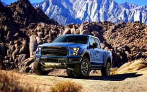 藍色福特 F-150 Raptor 卡車停放在沙漠小徑上，背景有山脈 — 汽車 壁紙