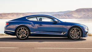 藍色 Bentley 跑車停泊在湖邊，遠方有山脈。