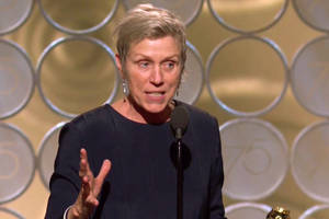 女性在金色圓形背景的舞台上發表獲獎感言。