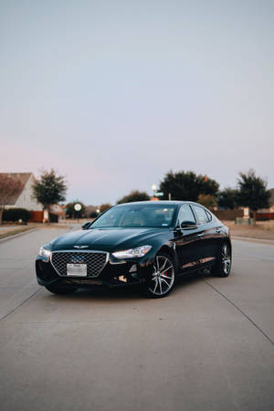 黑色Genesis G70房車停泊在住宅街道上，黃昏時分。