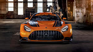 橙色 Mercedes-AMG GT3 賽車停放在陽光照射的廢棄倉庫中。