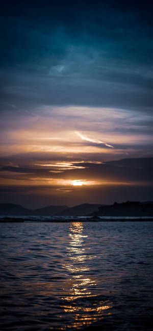 海上的夕陽，帶有金色倒影和暗色山丘 — 沙灘 壁紙