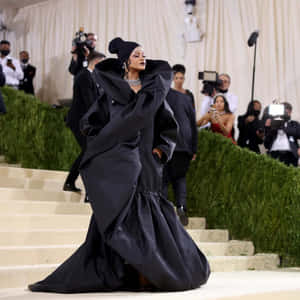 Rihanna 身穿黑色長袍，在正式活動中走下樓梯。