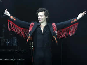 Harry Styles 身穿黑色西裝，搭配紅色流蘇和花卉刺繡，在舞台上表演。 — 哈里·斯泰爾斯 壁紙