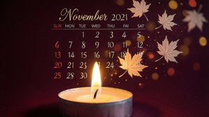 一支點燃的蠟燭，配以2021年11月的日曆和飄落的楓葉，呈現溫暖的散景效果。